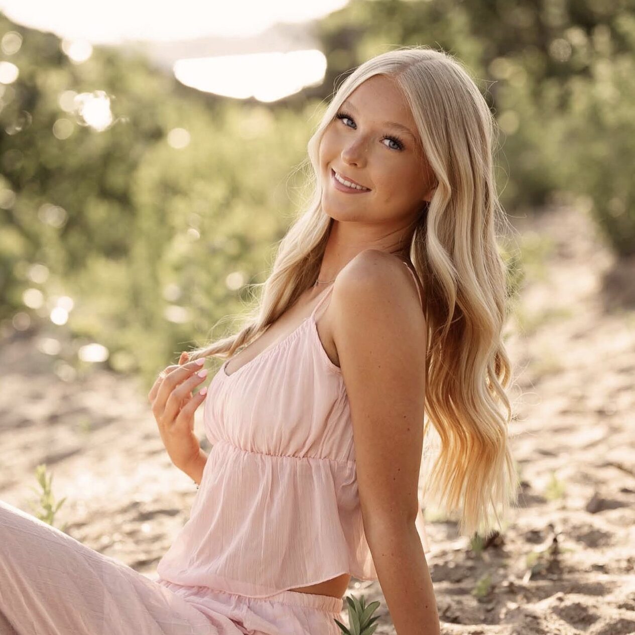 portrait of teenage girl sitting in a field smiling at camera