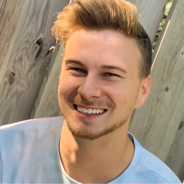 portrait of teenage boy leaning against wood fence smiling at camera